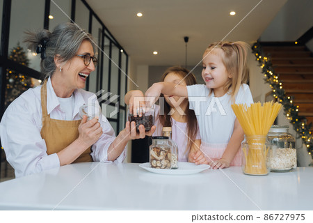 Grandmother and granddaughter are cooking on kitchen. Grandmother and granddaughter are cooking on kitchen. 86727975