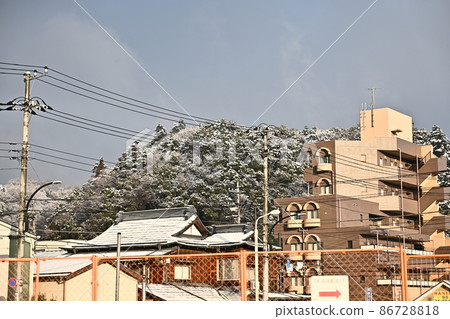 被建築圍欄包圍的建築物和前面有雪山的建築物 雪覆蓋的樹木在早晨的陽光下閃閃發光 86728818