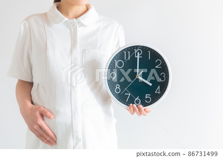 Working pregnant woman, nurse with a clock, evening / early morning 86731499