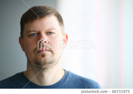 Portrait of young sad man in front of window Portrait of young sad man in front of window 86731975