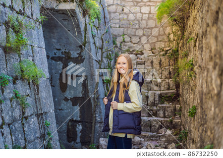 Young tourist woman enjoying a view of Kotor Bay, Montenegro. Kotor Old Town Ladder of Kotor Fortress Hiking Trail. Aerial drone view 86732250