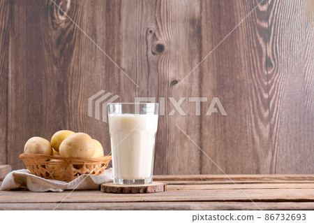 Vegan potato milk and potato on brown wooden background. Plant based alternative milk replacer and lactose free 86732693