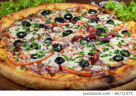 Pizza calzone with bacon and cheese, herbs and cherry tomatoes. With mozzarella, shrimps and octopuses, mussels and other products on a wooden background. Pizza calzone with bacon and cheese, herbs and cherry tomatoes. With mozzarella, shrimps and octopuses, mussels and other products on a wooden background. 86732975