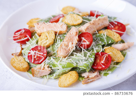 Caesar salad with red fish (salmon, trout), cherry tomatoes, croutons, parmesan cheese and romaine. Traditional American dish. Close-up, selective focus. 86733676