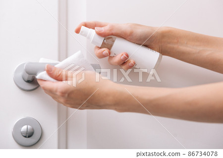 Cleaning white door handles with an antiseptic wet wipe and sanitizer spray. Disinfection in hospital and public spaces against corona virus. Woman hand using towel for cleaning home room door link. Cleaning white door handles with an antiseptic wet wipe and sanitizer spray. Disinfection in hospital and public spaces against corona virus. Woman hand using towel for cleaning home room door link. 86734078