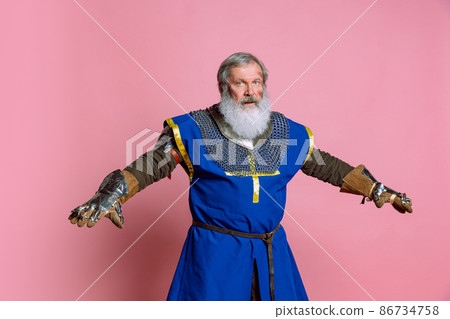 Portrait of senior grey bearded man, brave medieval warrior or knight in armored clothes with sword isolated on pink background. Comparison of eras, history, festival Portrait of senior grey bearded man, brave medieval warrior or knight in armored clothes with sword isolated on pink background. Comparison of eras, history, festival 86734758