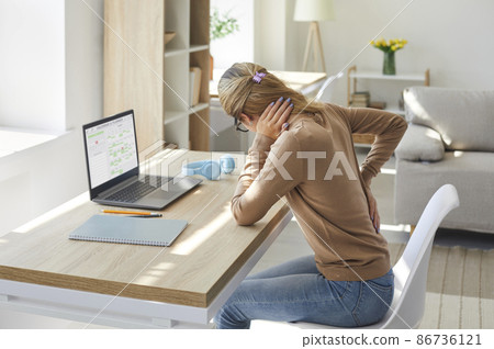 Tired woman who works on computer at desk in sedentary posture for a long time is feeling intense back pain. Unhappy stressed young lady suffering from radiculitis, spasm or pinched nerve inflammation 86736121