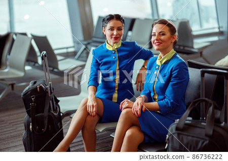 Joyful women stewardesses waiting for the flight at airport Joyful women stewardesses waiting for the flight at airport 86736222