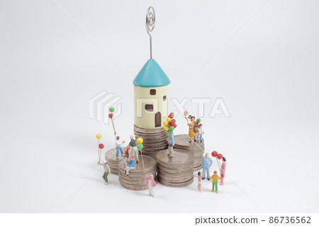 a  mini people, family standing on coins stacks with house model on the top stack. 86736562