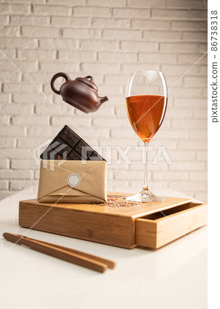 a tea table with tea and a wine glass in which Sheng Pu'er tea is poured to demonstrate the color a tea table with tea and a wine glass in which Sheng Pu'er tea is poured to demonstrate the color 86738318