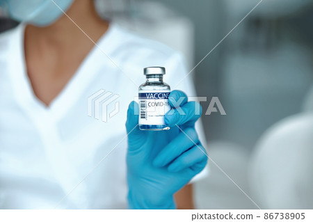 COVID-19 vaccine in researcher hands, female doctor holds syringe and bottle with vaccine for coronavirus cure. 86738905