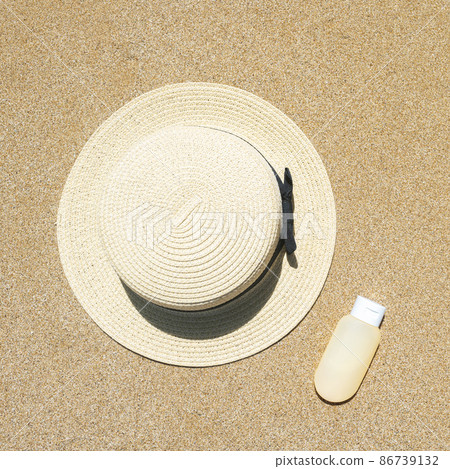 Summer straw hat and sunscreen lying on sand of beach. Travel, holiday, summertime concept. Copy space. Top view. Flat lay 86739132
