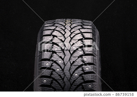 winter studded tire front view close-up on a black background tread blocks and lamellas tire safety 86739158