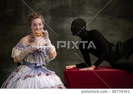 Young beautiful woman in image of medieval royal person in renaissance style dress and her page isolated on dark vintage background. 86739361