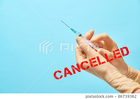 Cancelled sign. Doctor's hands in gloves hold a syringe with a needle Cancelled sign. Doctor's hands in gloves hold a syringe with a needle 86739362