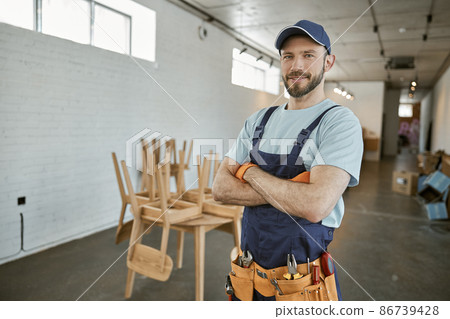 Cheerful male worker in cap standing in workshop Cheerful male worker in cap standing in workshop 86739428