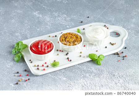 Popular sauces ketchup dijon mustard and mayonnaise in bowls on tray Popular sauces ketchup dijon mustard and mayonnaise in bowls on tray 86740040