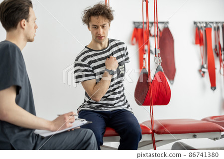 Man having consultation with physiotherapist at rehabilitation office Man having consultation with physiotherapist at rehabilitation office 86741380