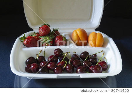 Berries and fruits in a Styrofoam container on the table 86741490