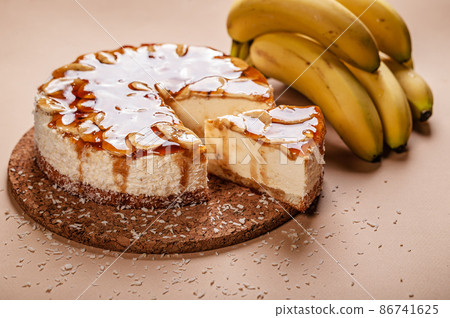 Close-up Banana cheesecake with caramel on a beige background. Homemade delicious pastries. Sweet tasty dessert. Copy space Close-up Banana cheesecake with caramel on a beige background. Homemade delicious pastries. Sweet tasty dessert. Copy space 86741625