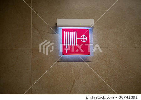 Illuminated fire hose sign on the wall. 86741891