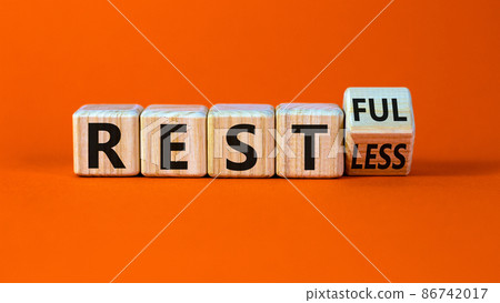 Restless or restful symbol. Turned the wooden cube, changed the word 'restless' to 'restful'. Beautiful orange table, orange background, copy space. Business and restless or restful concept. Restless or restful symbol. Turned the wooden cube, changed the word 'restless' to 'restful'. Beautiful orange table, orange background, copy space. Business and restless or restful concept. 86742017