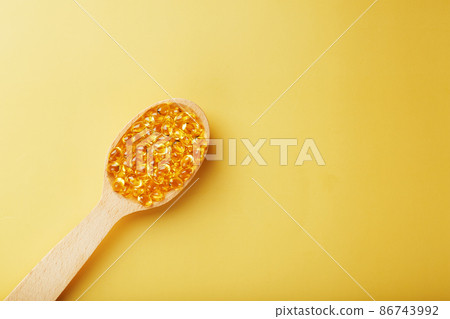 Vitamin D3 Capsules in a spoon with other vitamin D3 capsules around them on a yellow background Vitamin D3 Capsules in a spoon with other vitamin D3 capsules around them on a yellow background 86743992