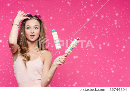 Funny girl holding marshmallows on stick under Funny girl holding marshmallows on stick under 86744894