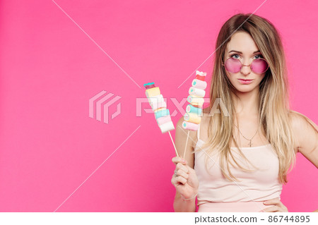 Funny girl holding marshmallows on stick under 86744895