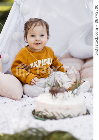 Happy toddler posing in wigwam with his birthday cake Happy toddler posing in wigwam with his birthday cake 86745300