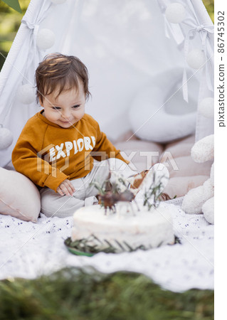 Happy toddler posing in wigwam with his birthday cake Happy toddler posing in wigwam with his birthday cake 86745302