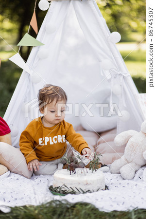 Caucasian child playing in wigwam near his birthday cake 86745307