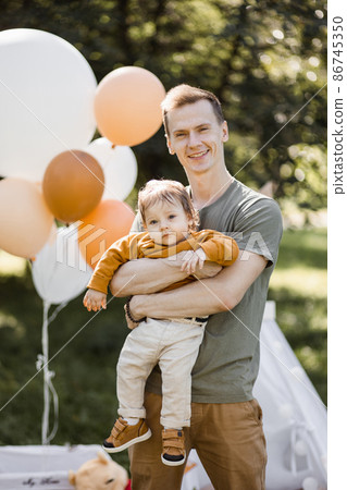 Caring father posing near wigwam with cute son on hands 86745350