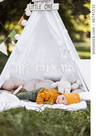 Happy baby boy lying inside teepee tent outdoors 86745532