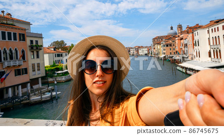 Travel blogger Venice italy. Photographer girl with smartphone in Venice San Marco square. Paint building house in travel Europe Venezia city. Hispter tourist using her phone outdoors. Travel blogger Venice italy. Photographer girl with smartphone in Venice San Marco square. Paint building house in travel Europe Venezia city. Hispter tourist using her phone outdoors. 86745675