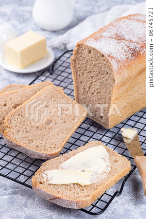 Homemade no knead sandwich bread with butter, on cooling rack, vertical 86745721