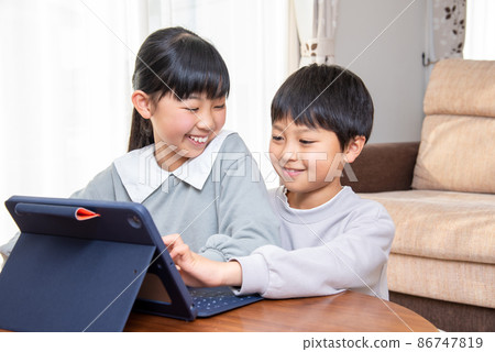 Elementary school boys and girls using tablet PCs in the living room Elementary school boys and girls using tablet PCs in the living room 86747819