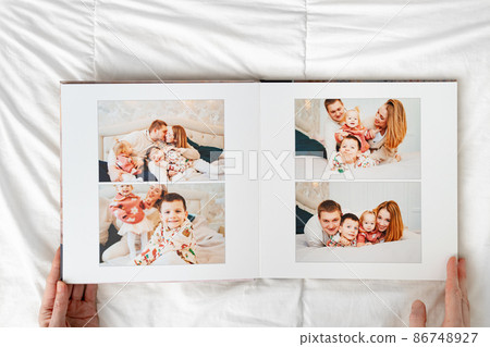 a hands with a book with photos of big family at home on a white background. 86748927