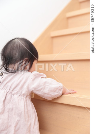 0 year old baby girl trying to climb the flooring stairs 86749319