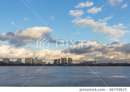 Urban winter landscape from frozen lake. Waste processing plant behind lake Urban winter landscape from frozen lake. Waste processing plant behind lake 86749625