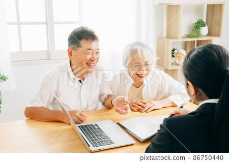 A woman in a suit and an elderly couple explaining on a computer A woman in a suit and an elderly couple explaining on a computer 86750440