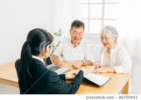 A woman in a suit and an elderly couple explaining on a computer A woman in a suit and an elderly couple explaining on a computer 86750441