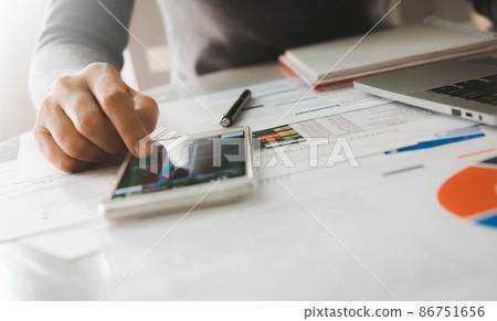 Businesswoman analyze business report graph and finance chart using smartphone and computer laptop at corporate office. 86751656