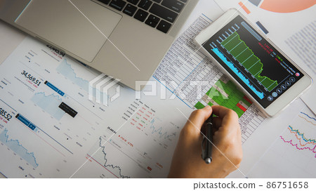Businesswoman analyze business report graph and finance chart using smartphone and computer laptop at corporate office. 86751658