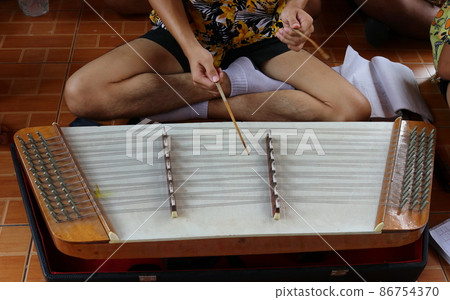 Teen age playing Thai dulcimer. Teen age playing Thai dulcimer. 86754370