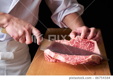 A cook who cuts sirloin steak with a kitchen knife Domestic Japanese black beef A cook who cuts sirloin steak with a kitchen knife Domestic Japanese black beef 86754384