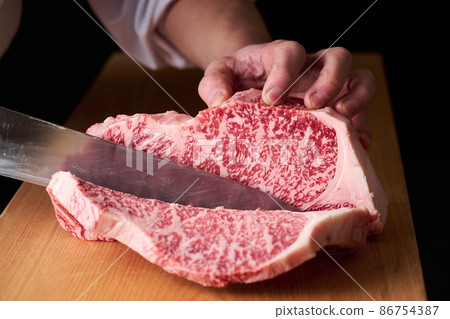 A cook who cuts sirloin steak with a kitchen knife Domestic Japanese black beef 86754387