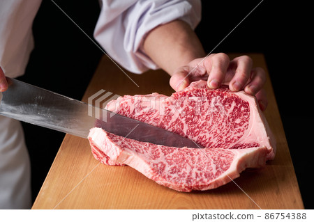 A cook who cuts sirloin steak with a kitchen knife Domestic Japanese black beef 86754388