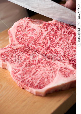 A cook who cuts sirloin steak with a kitchen knife Domestic Japanese black beef 86754398