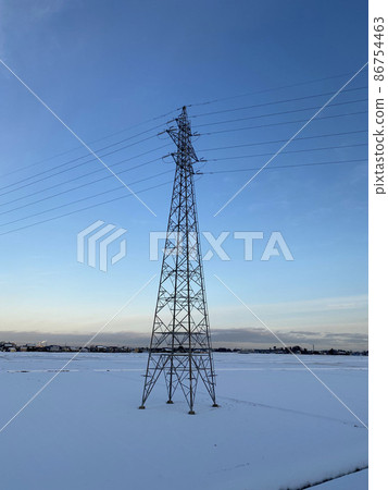 A steel tower standing in the middle of a paddy field that turned white in the calm morning air 86754463